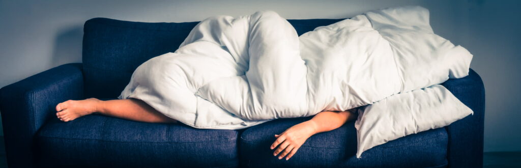 lazy person lying on a sofa, covered by. white duvet. Illustrating the concept of a lazy customer.